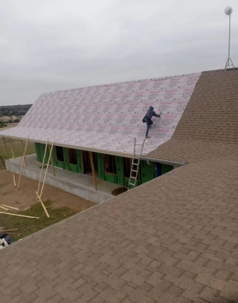 Worker preparing underlayment for a metal roof installation in Clovis